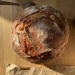 a loaf of sourdough boule on a wooden background.