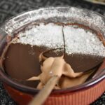 double chocolate creme brulee in a purple ramekin with a wooden spoon in the custard.