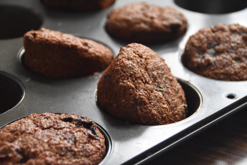 Prune and bran muffins in a muffin tin.