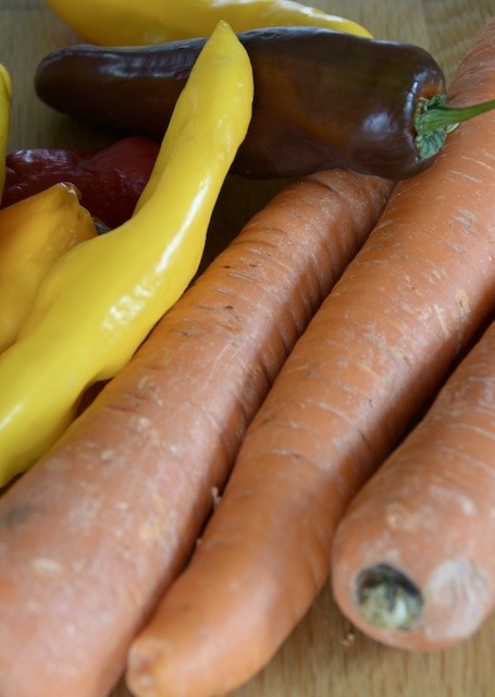 Some whole carrots and colorful sweet peppers next to each other on the table.