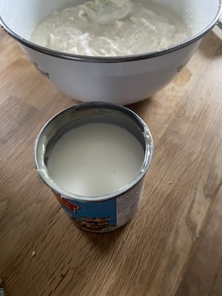 A can filled with milk in front of a bowl of cassava batter.