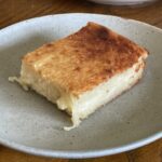 A slice of cassava cake on a grey plate.