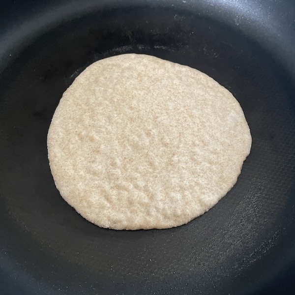 pita bread in a pan before flipping at the parcooking stage.