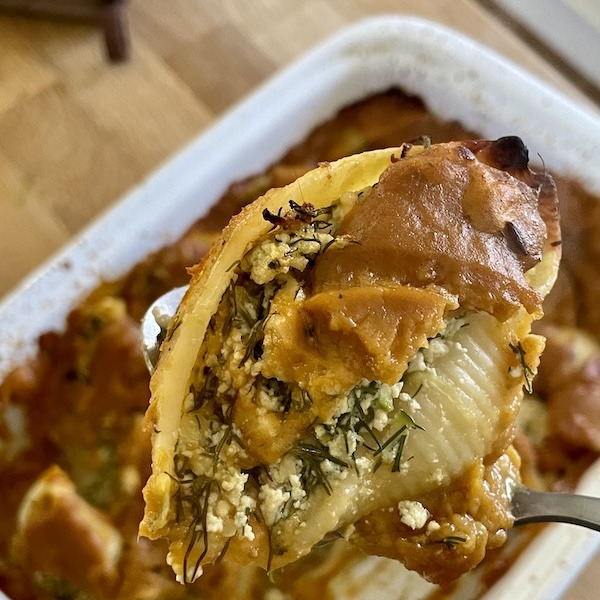 a close up of a baked tofu stuffed shell with sweet potato sauce
