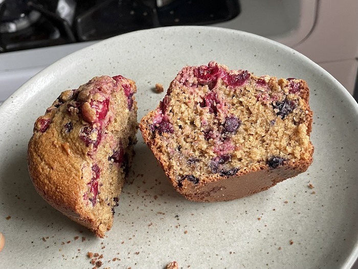 A cranberry oatmeal muffin cut in half to reveal the crumb and fruit.