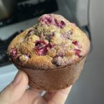 A cranberry oatmeal muffin held up in a hand