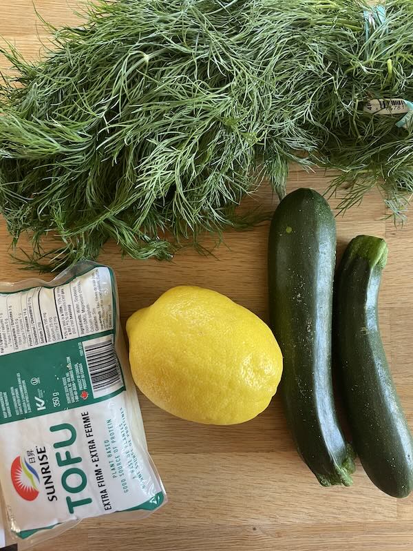 zucchini, dill, lemon, and tofu on a table