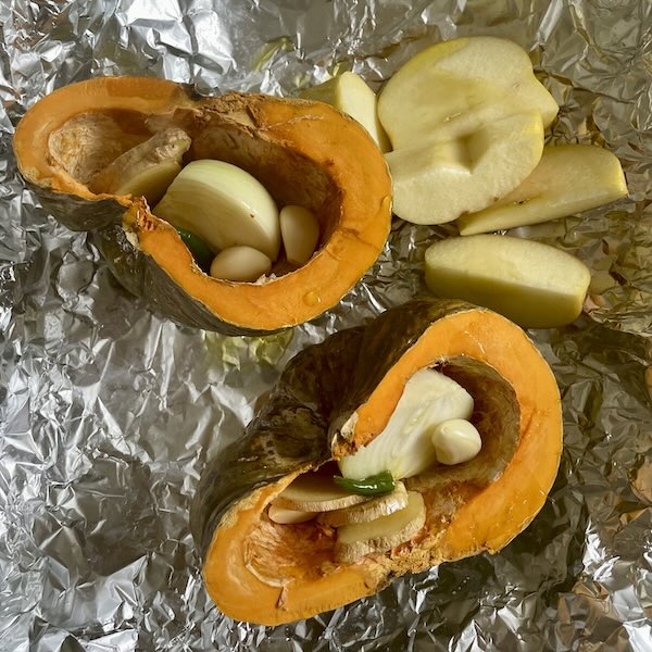 kabocha squash, aromatics, and apples in foil ready to roast in the oven.