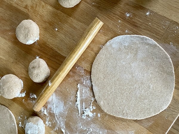 rounds of dough being rolled out to become pita bread.