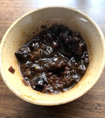 dried prunes in a bowl that have been reconstituted in water.