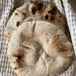 a couple of spelt pita breads on a kitchen towel.