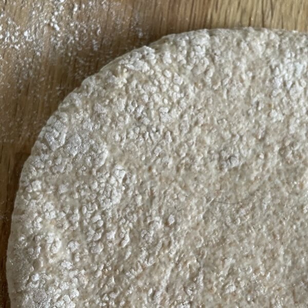 an uncooked pita bread with too much flour.