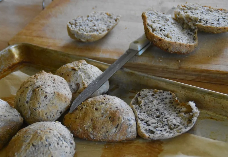 a batch of seeded buns on a cutting board ready to be made into sandwiches