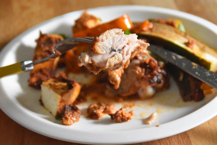 a close up of a piece of chicken in the sun-dried tomato and walnut casserole