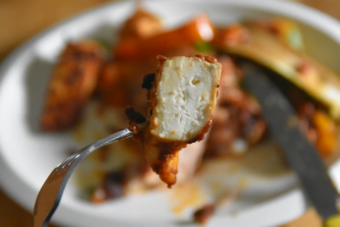 close up of piece of paneer in sun dried tomato and walnut casserole