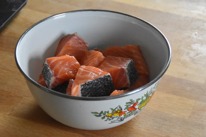 Chunks of salmon filet in a bowl ready to marinate with maple syrup.