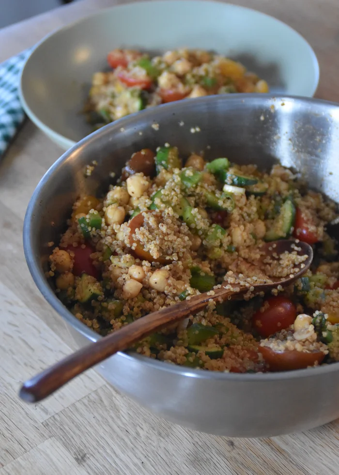 a batch of high protein quinoa salad with chickpeas next to a serving of quinoa salad.