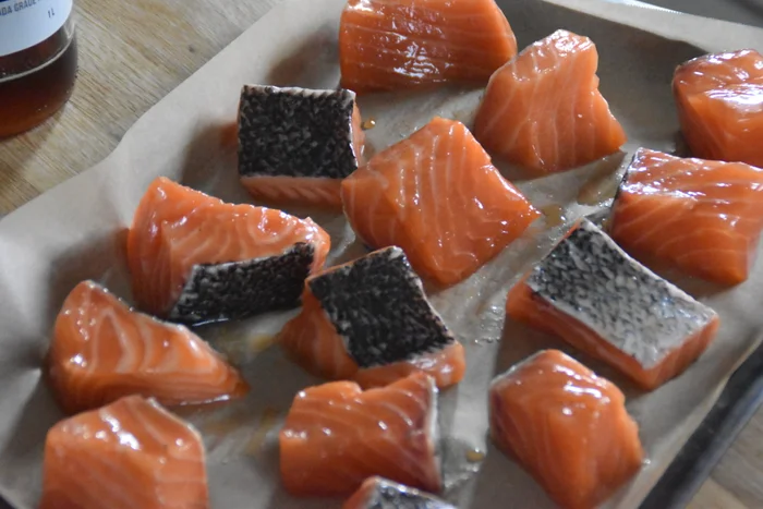 Chunks of raw maple syrup salmon on a baking tray ready to be cooked.