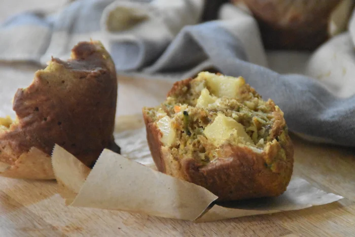 a pineapple morning glory muffin torn in half to reveal a lot of fruit on the inside.